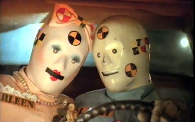 two crash test dummies sitting in the front seat of a car canoodling