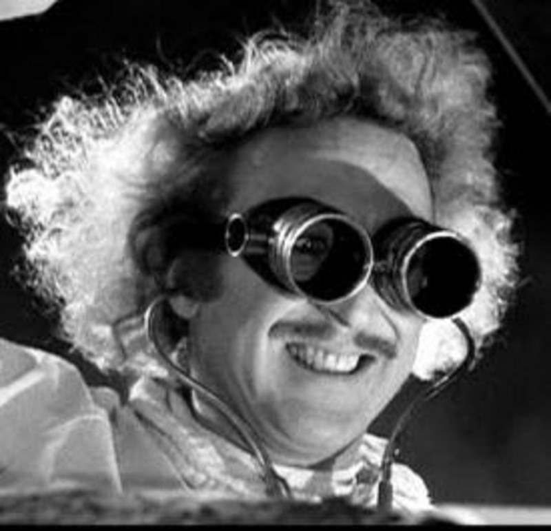 Still of Gene Wilder from Young Frankenstein. A black and white image of a mad scientist crinning while wearing long tinted goggles.