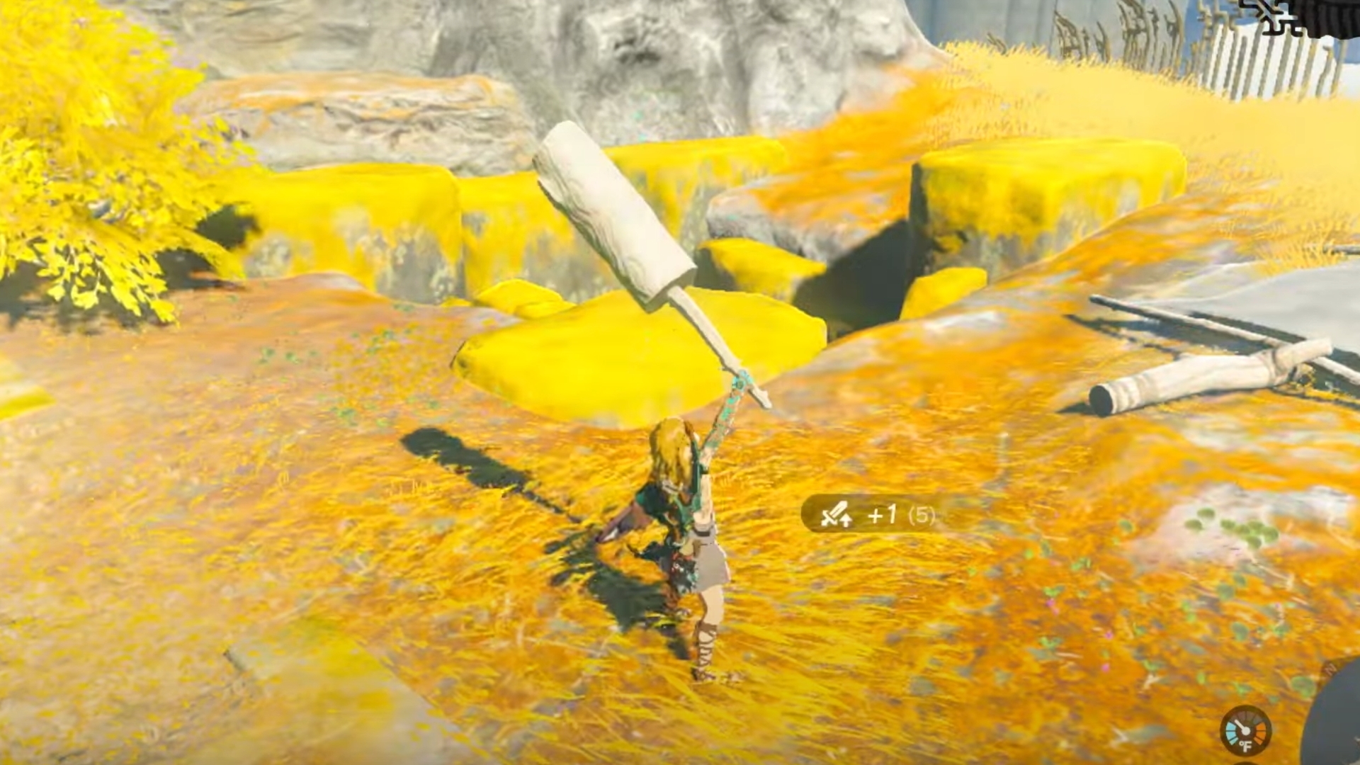 Image from Zelda Tears of the Kingdom (video game). A character (Link) holds a wooden log high above their head in a mountain meadow.