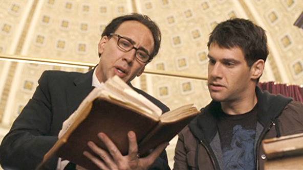 Movie still of a man (Nicolas Cage) in glasses studiously reading an old book