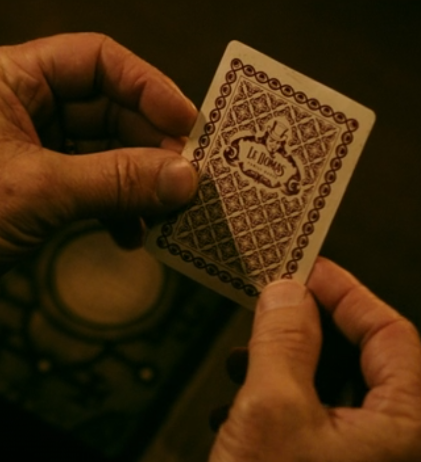 A pair of hands holds a single playing card face down.